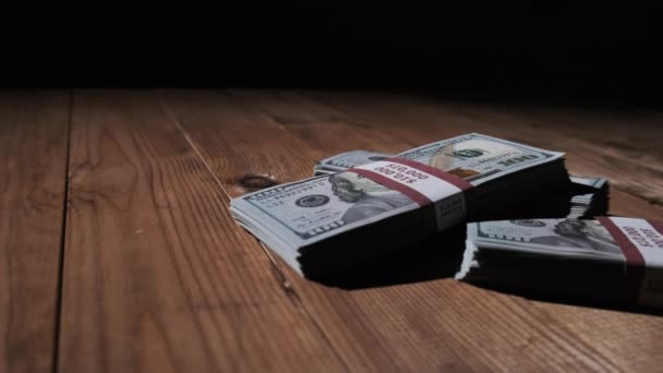 Три пачки банкнот номиналом 10000 американских долларов лежат на деревянном столе — стоковое видео