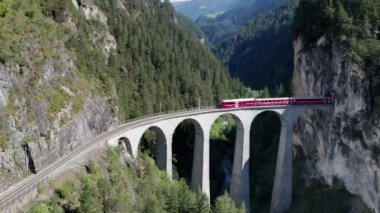 İsviçre Alplerindeki Landwasser Viaduct boyunca ilerleyen bir Kızıl Trenin Hava Görüntüsü