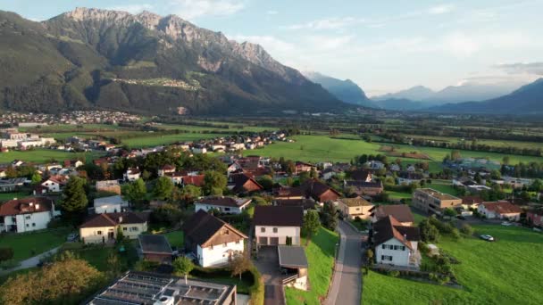Vista aérea de Liechtenstein con casas en campos verdes en Alpes Mountain Valley — Vídeos de Stock