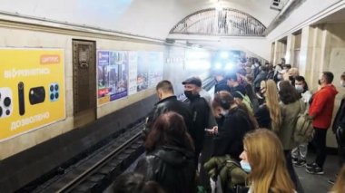 Metrodaki platformda maskeli insanlar treni bekliyor.