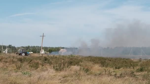 Feuer Trockenrasen auf Feld in der Nähe des Dorfes im Sommer, Wildfeuer von Trockenrasen — Stockvideo