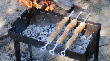 Sosisler portatif ızgarada pişiriliyor. Kapatın, barbekü.