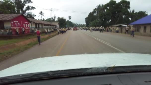 Tłum afrykańskich dzieci szkolnych wybiegają na drogę w lokalnej wiosce, jazdy samochodem, Zanzibar — Wideo stockowe