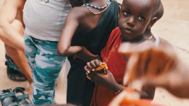 Helyi afrikai éhes gyermek eszik papírt az utcán az emberek között, Zanzibár, Afrika — Stock videók