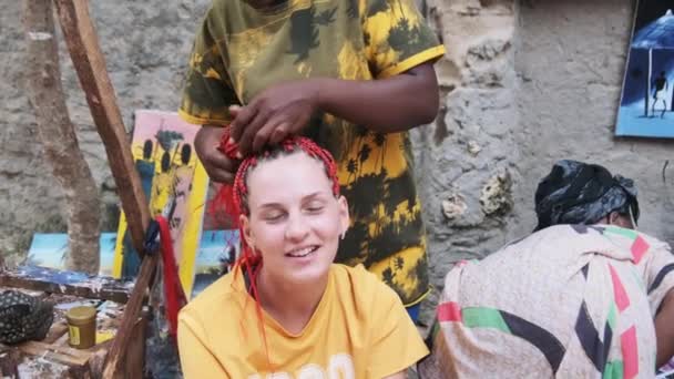 Africká žena tkaní africké copánky s Red Kanekalon Outdoor, Zanzibar Afrika — Stock video