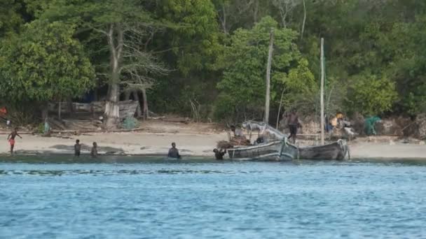 Locale africano villaggio di pescatori, La gente del posto scaricare la barca da pesca Dhow al largo della costa — Video Stock