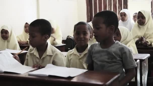 Niños en una escuela primaria africana se sientan en escritorios en un aula, Zanzíbar — Vídeo de stock