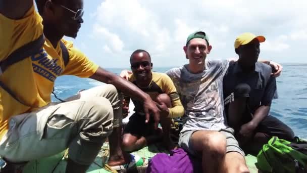 Joyful White tourist with Africans sings a song moving on an old boat in Ocean — Stock Video