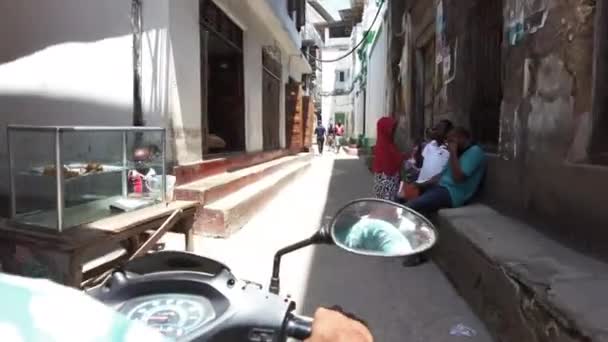Jazda na motocyklu przez wąskie brudne uliczki Stone Town z ubogich Afrykańczyków — Wideo stockowe