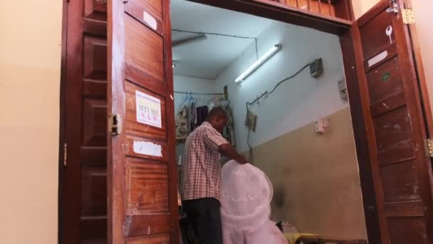 Αφρικανική φτωχό εργαστήριο ραπτικής σε ένα μικρό δωμάτιο, μαύρο αρσενικό ράφτη εργασία με ιστό — Αρχείο Βίντεο