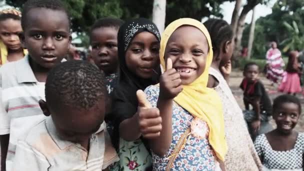 幸せな地元のアフリカの子供たちは親指のサインと好奇心を示すZanzibar村 — ストック動画
