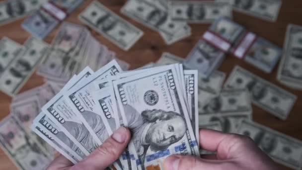 Dólares en manos masculinas en el fondo de la mesa con dinero — Vídeo de stock