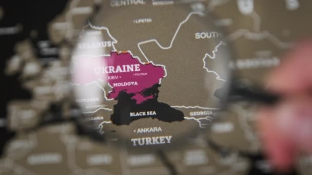 Ucrania en el mapa mundial bajo una lupa de lupa, atención mundial a la guerra — Vídeo de stock