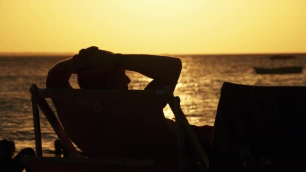 Güneş 'te uzanan adamın silueti Okyanus' un Sunset 'ine bakıyor, Zanzibar — Stok video
