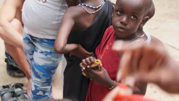 Місцеві африканські голодні діти їдять папір на вулиці серед людей, Занзібар, Африка — стокове відео