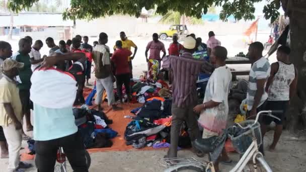 Africano pessoas compram roupas de segunda mão em uma loja ao ar livre na África, Zanzibar — Vídeo de Stock