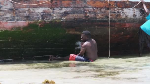 ザンジバルのロータイドにある海岸の藻類からボートを掃除するアフリカの漁師 — ストック動画