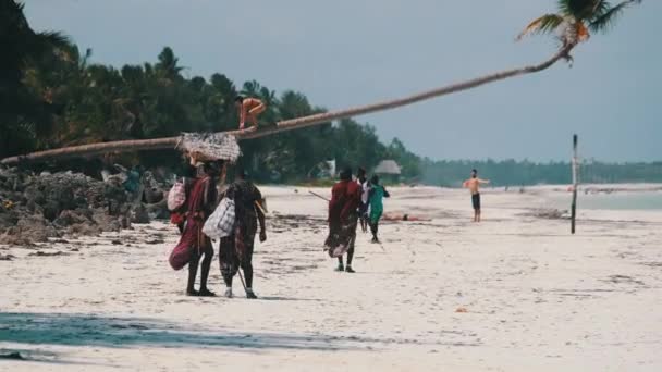 Прогулянка Масаї вздовж тропічного пляжу океаном серед туристів на острові Занзібар. — стокове відео