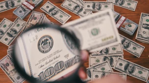 Cent dollars inspectant sous le verre grossissant sur fond d'argent — Video