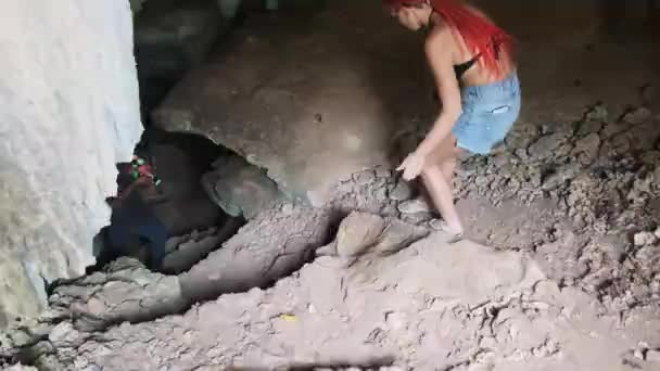 Frau erkundet Stalaktiten in einer tiefen dunklen Höhle und leuchtet mit Taschenlampe — Stockvideo