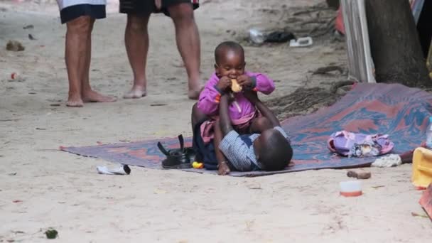 Místní africký špinavý šťastný chlapec a dívka sedět na zemi, hrát a usmívat se, Zanzibar — Stock video