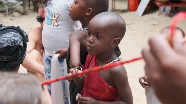 Miejscowy afrykański głodny dziecko zjada papier na ulicy wśród ludzi, Zanzibar, Afryka — Wideo stockowe