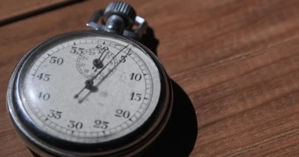 Een antieke stopwatch ligt op houten tafel en telt de seconden — Stockvideo