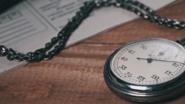 Vintage cronómetro se encuentra en el escritorio de madera con documentos antiguos y cuentos segundos — Vídeos de Stock
