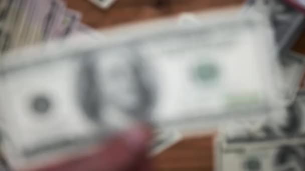 Сто долларов, проверяющих под увеличительным стеклом на денежном фоне — стоковое видео
