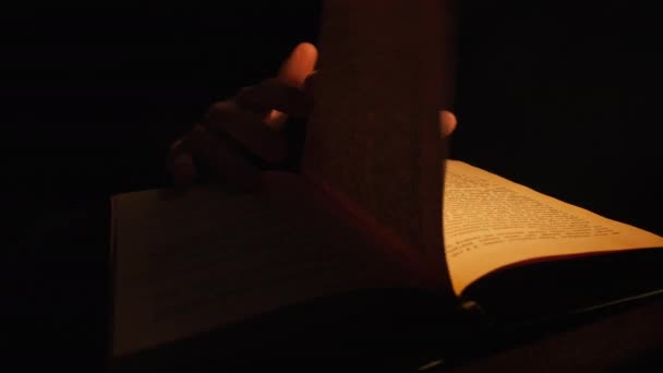 Читання старої книги під вінтажним жовтим освітленням лампи — стокове відео