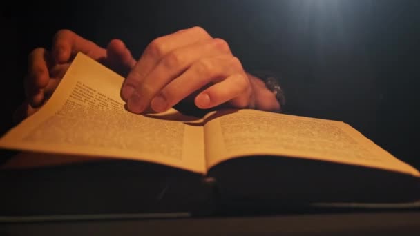 Читання старої книги під атмосферним жовтим освітленням лампи — стокове відео