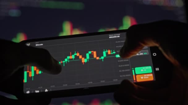 スマートフォン画面でビットコインチャートを確認する投資家 — ストック動画