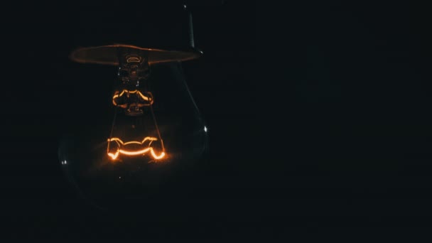 Glödlampan tänds och släcks långsamt på svart bakgrund — Stockvideo