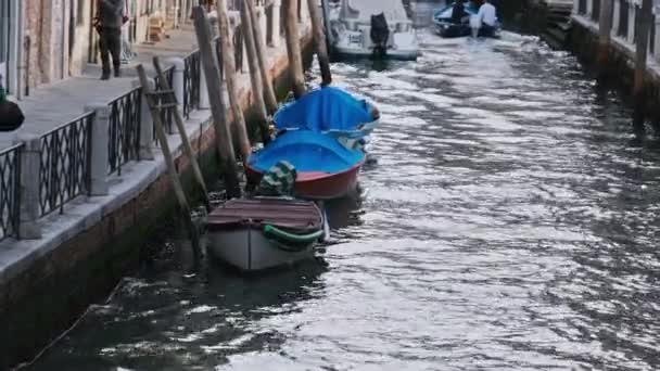 Узкие каналы Венеции с гондолами, припаркованными на воде между красочными домами — стоковое видео