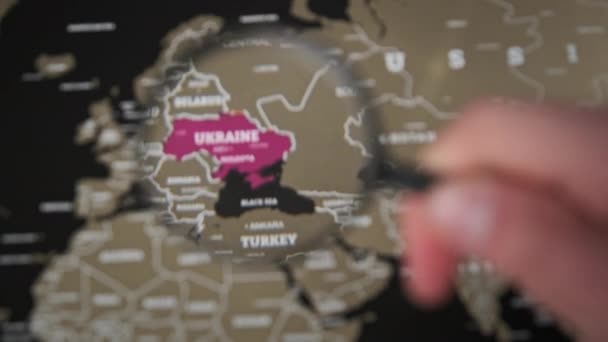 Украина на карте мира под лупой лупы, внимание всего мира к войне — стоковое видео