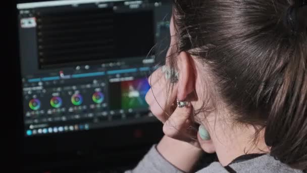 Редактор видео для женщин сидит за ноутбуком и обрабатывает видео материал дома — стоковое видео