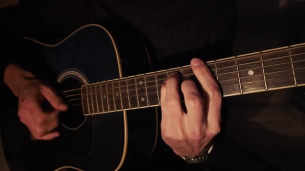 Homme jouant de la guitare acoustique à la maison dans l'éclairage chaud sombre atmosphérique — Video