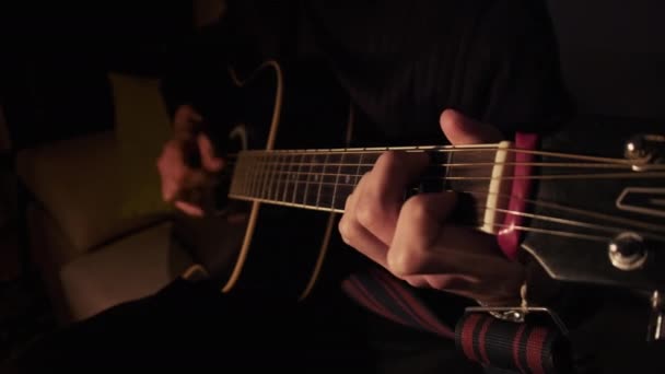 Man gra na gitarze akustycznej w domu w atmosferze ciemne ciepłe oświetlenie — Wideo stockowe