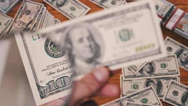 Сто долларов заглядывают под увеличительное стекло над денежным столом — стоковое видео