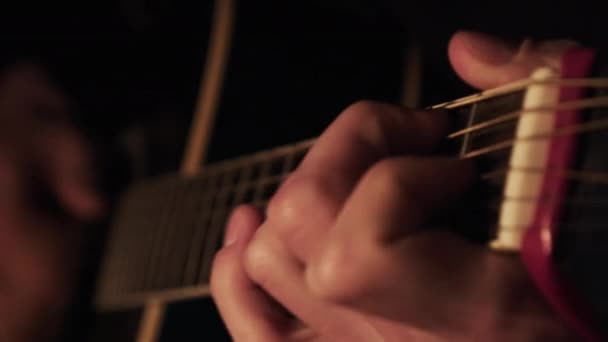 Hombre tocando la guitarra acústica en casa en la atmósfera oscura cálida iluminación — Vídeo de stock