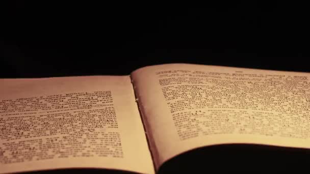 Lectura de un libro antiguo bajo iluminación de lámpara amarilla vintage — Vídeo de stock