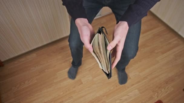 Homem jovem engraçado mostra uma carteira cheia de dinheiro — Vídeo de Stock