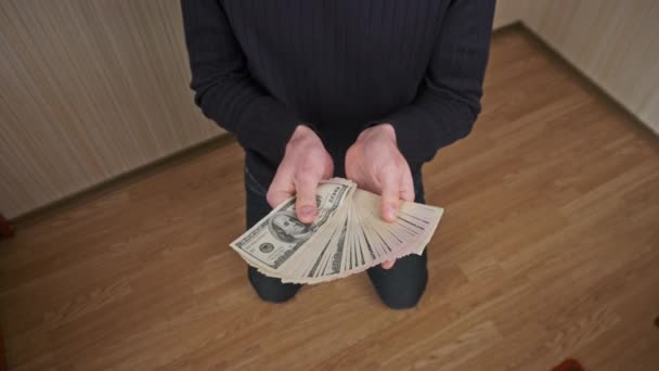 Young Man on His Knees Shows a Lot of Dollar Bills Spread Out Like a Fan — Stock Video