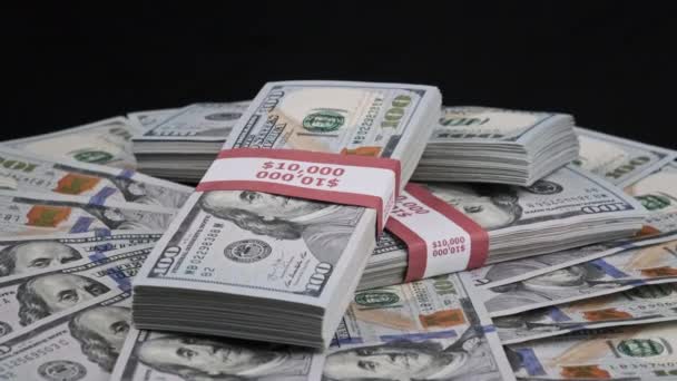 Пачки долларов лежат на груде денег и вращаются на черном фоне — стоковое видео