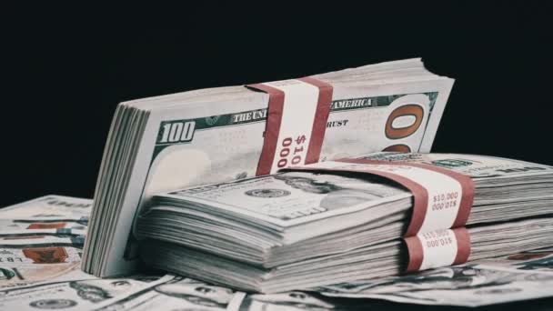 Pakiety dolarów leżące na stosie pieniędzy i obracać się na czarnym tle — Wideo stockowe