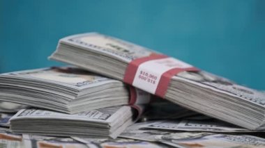 Para Yığını Üzerinde Yatan ve Mavi Arkaplanda Döndüren Dolar Paketleri