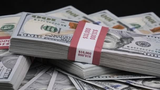 Paquetes de dólares que yacen sobre una pila de dinero y giran sobre el fondo negro — Vídeo de stock
