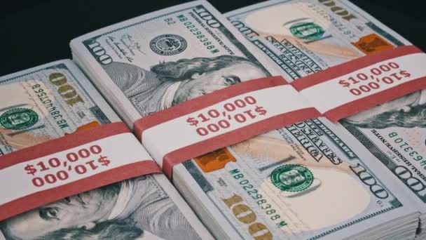 Tres pilas de 10000 dólares americanos Los billetes en paquetes bancarios giran — Vídeos de Stock