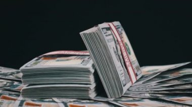 Para Yığını Üzerinde Yatan ve Siyah Arkaplanda Dönen Dolar Paketleri