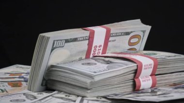 Para Yığını Üzerinde Yatan ve Siyah Arkaplanda Dönen Dolar Paketleri